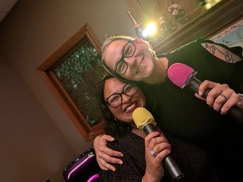 Two smiling guests sharing microphones at Jen’s Guesthouse