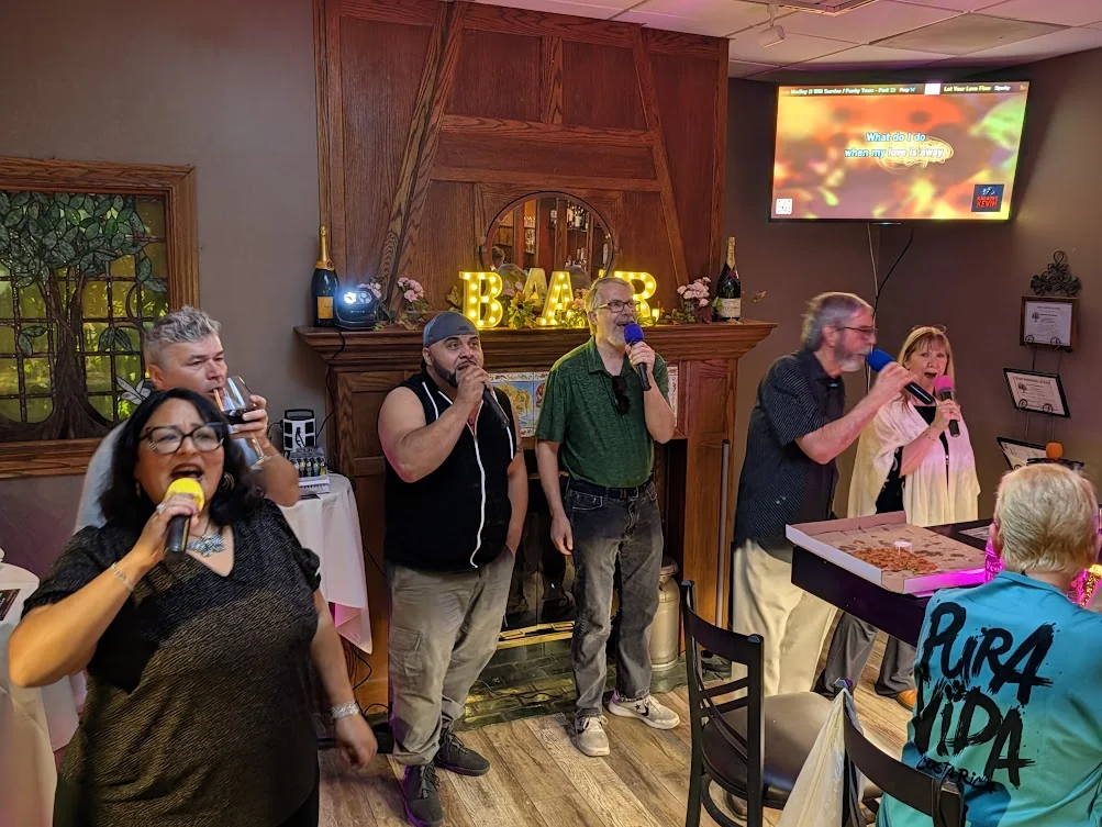Five guests singing karaoke by the fireplace at Jen’s Guesthouse