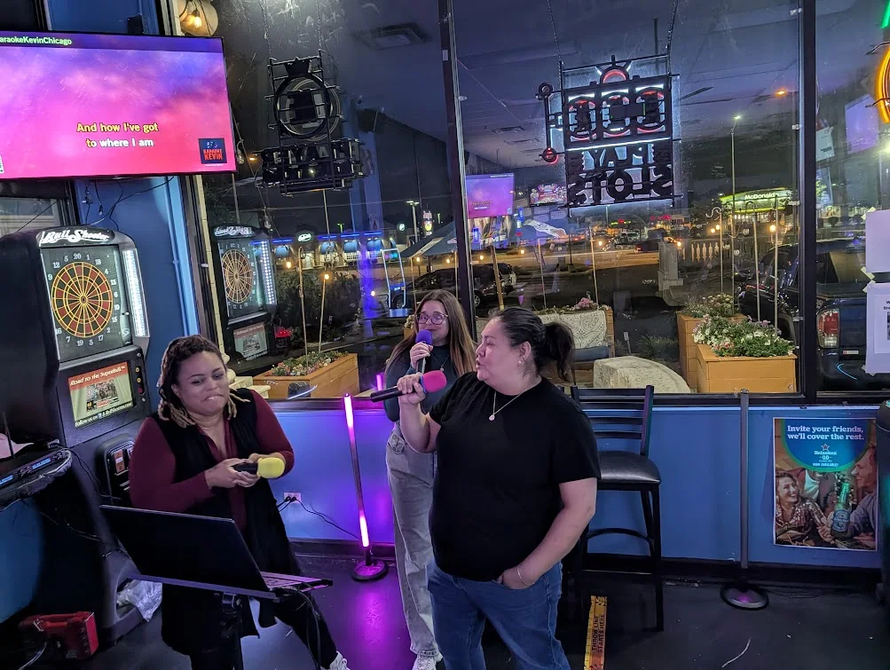 Guests singing beside the Sam’s Bar and Gaming window sign